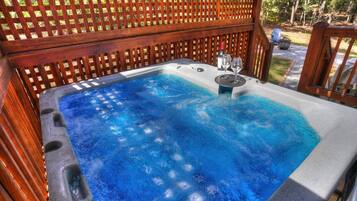A hot tub with a wooden lattice backdrop, surrounded by a wooden deck.
