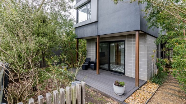 A modern house with a patio, a wooden deck, and a large window. - Harmony on Nautilus Inverloch (Inverloch)
