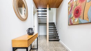 A staircase with a wooden handrail and a black metal railing, leading to an upper floor.