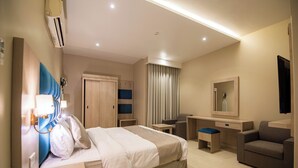 A hotel room with a bed, desk, chair, and a mirror. - Granada Palace Inn (Riyadh)