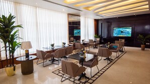 A modern conference room with glass tables, comfortable chairs, and a large screen displaying a sports event. - Granada Palace Inn (Riyadh)