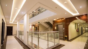 A modern hotel lobby with a glass railing, a staircase, and a polished marble floor. - Granada Palace Inn (Riyadh)