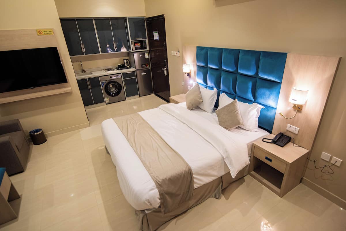 Una camera d'albergo con un letto grande, una televisione, una lavatrice e un angolo cottura.