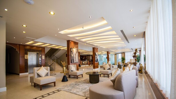 A spacious lobby with a modern design, featuring a large sofa, armchairs, a coffee table, and a staircase. - Granada Palace Inn (Riyadh)