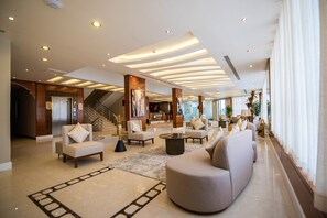 A spacious lobby with a modern design, featuring a large sofa, armchairs, a coffee table, and a staircase. - Granada Palace Inn (Riyadh)