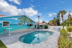 Una piscina con un murale tropicale, posti a sedere all'aperto e vista sull'oceano.