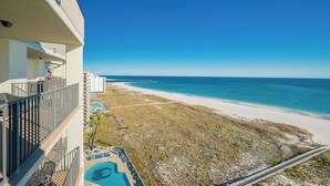 A hotel with a pool, a beach view, and a clear sky.