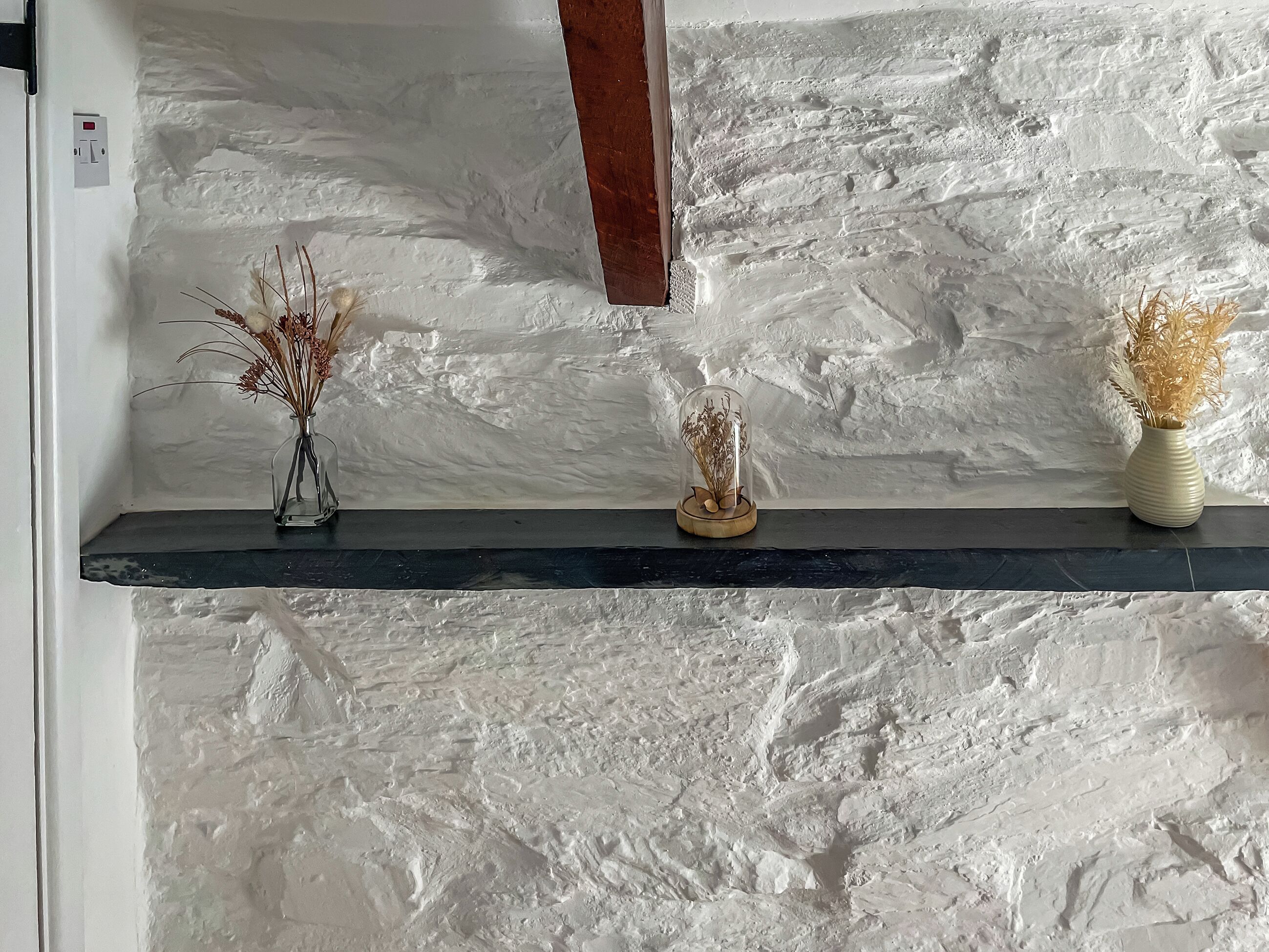 Una repisa con tres jarrones frente a una pared texturizada.