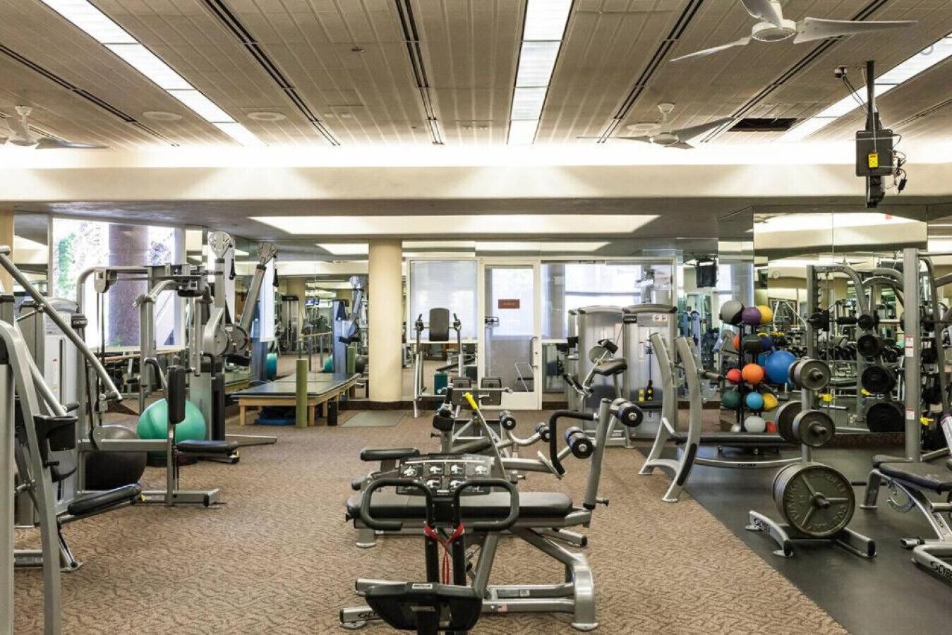 Een sportschool met diverse fitnessapparaten, waaronder krachtapparaten, losse gewichten en cardio-apparaten.