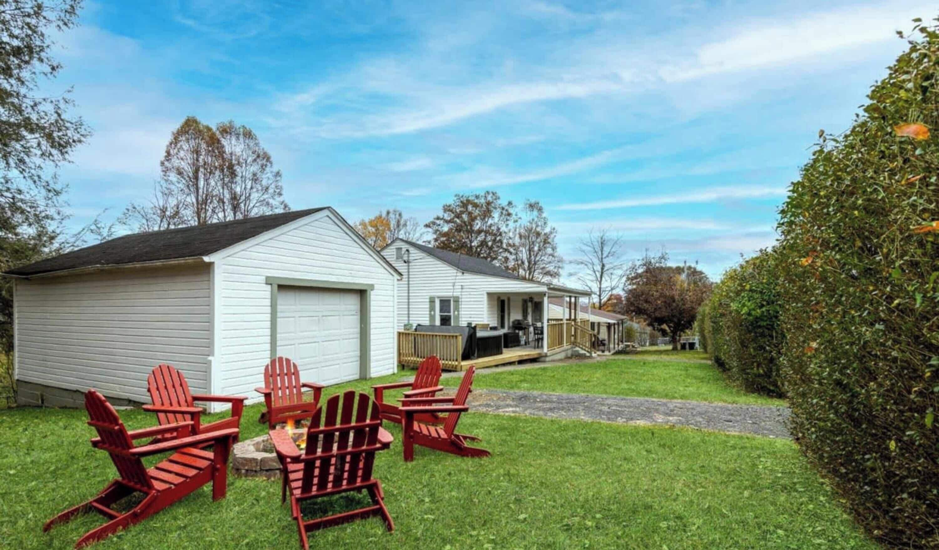 A two-story house with a covered porch and a fire pit in the yard.