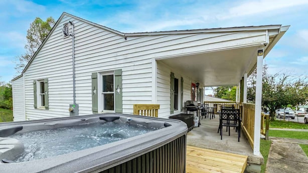 A house with a hot tub on the porch, a covered patio with outdoor furniture, and a garage.