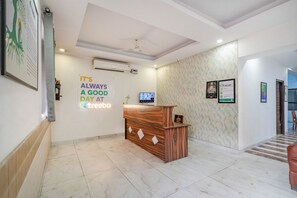 A reception area with a wooden desk, a wall-mounted TV, and a motivational quote. - Treebo Modern Stays (Noida)