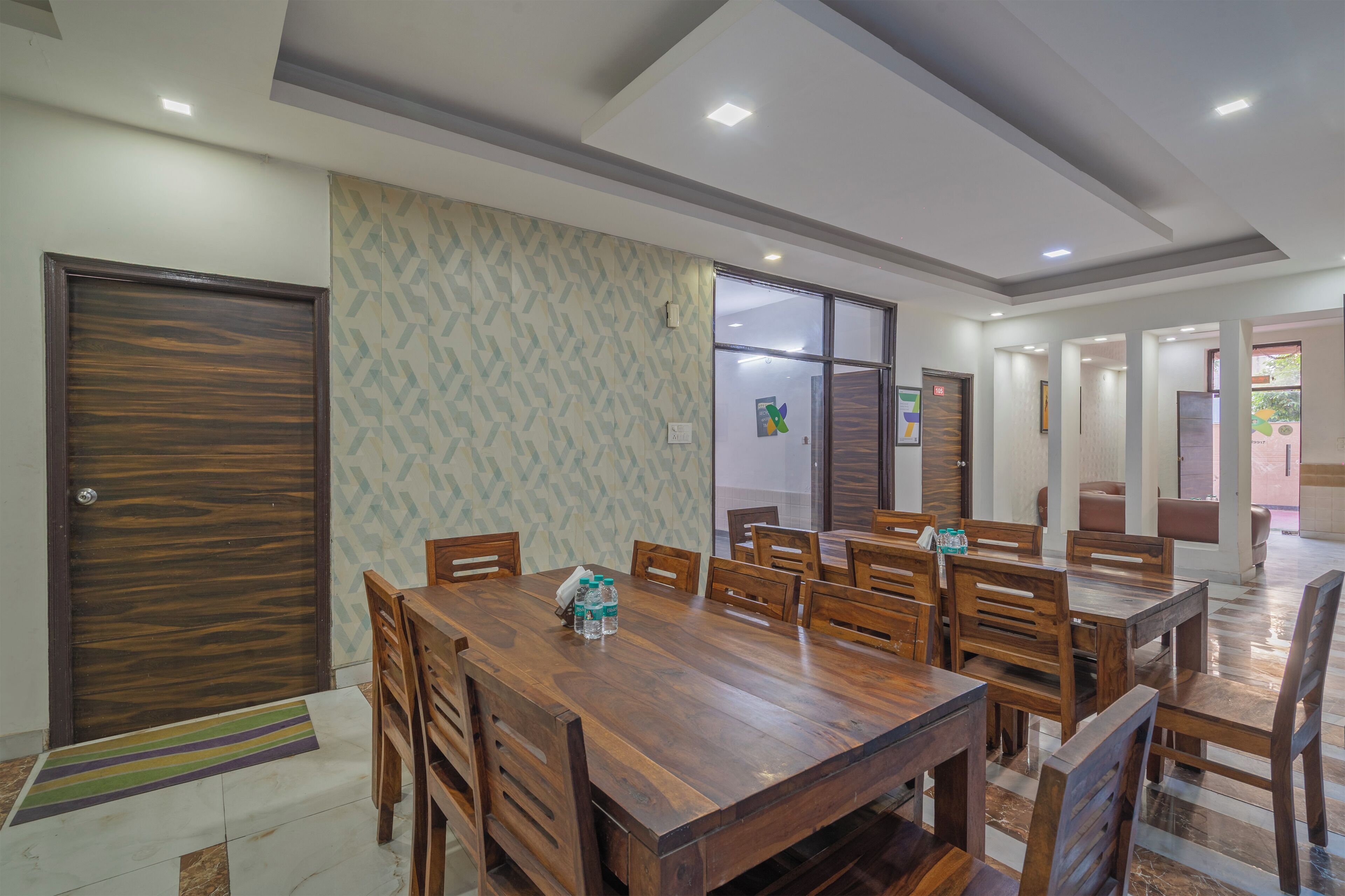 Un comedor amplio con una gran mesa de madera y sillas, un muro con diseño estampado y una puerta con textura.