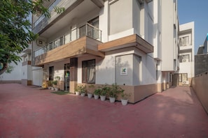 A multi-story building with a balcony, potted plants, and a clear sky. - Treebo Modern Stays (Noida)