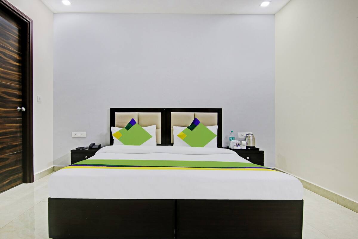 A hotel room with a bed, a nightstand, a phone, and a water bottle.