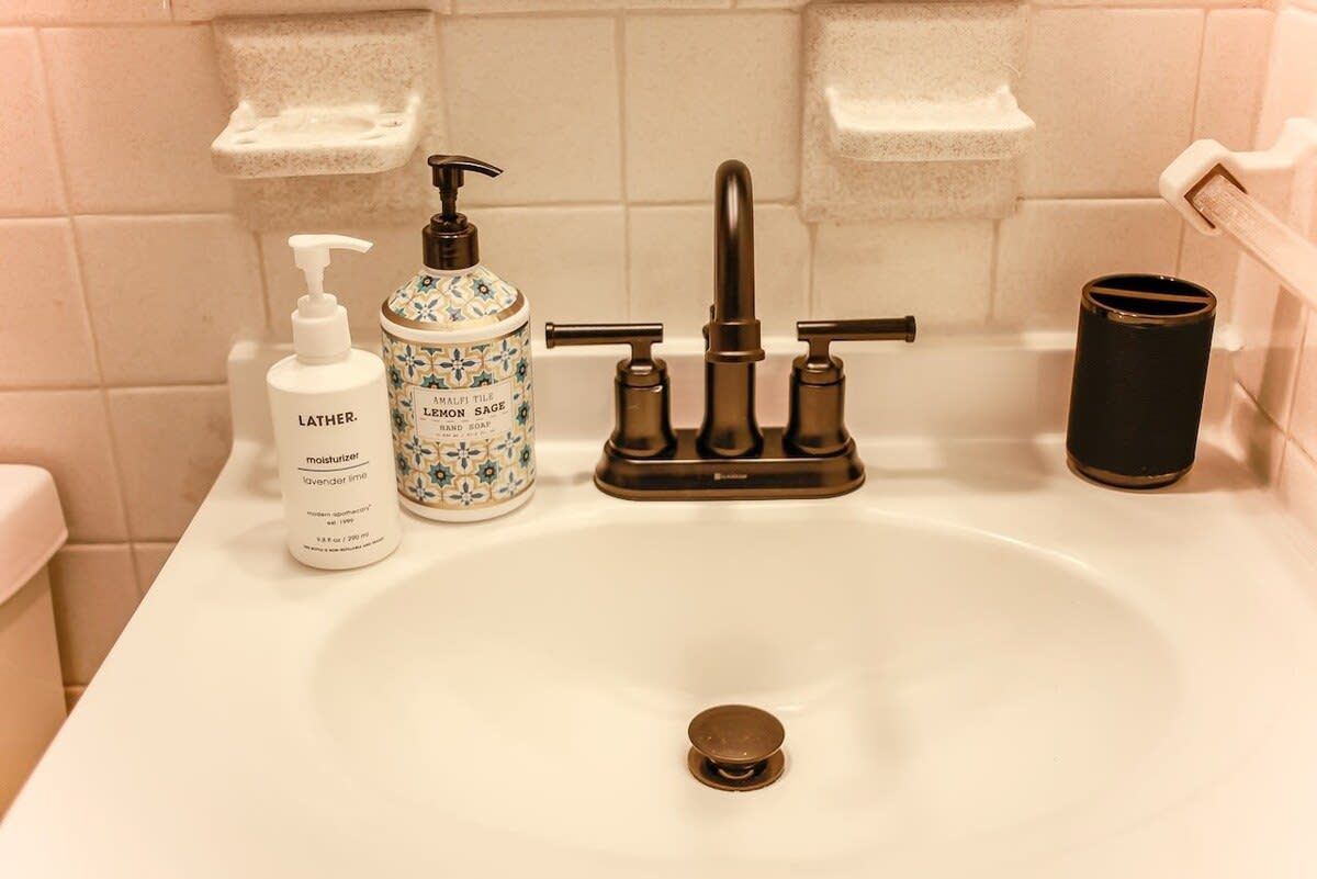 A bathroom sink with a faucet, a soap dispenser, and a soap bottle.