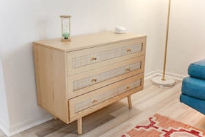 Une commode en bois avec trois tiroirs, un petit sablier et un objet blanc posé sur le dessus.
