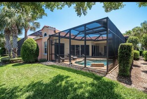 A modern house with a glass-enclosed patio and a swimming pool. - Great Floor Level Condo in Gated Community (Estero)