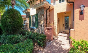 A two-story house with a stone facade, green shutters, and a number plaque. - Great Floor Level Condo in Gated Community (Estero)