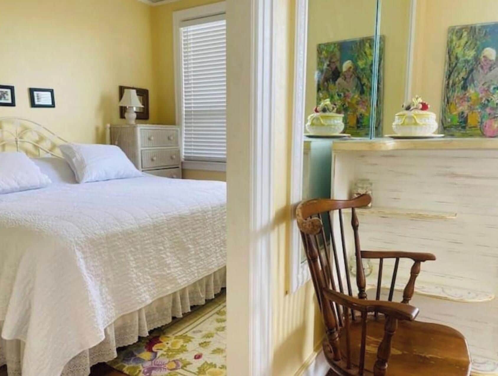 Een slaapkamer met een bed, nachtkastje, stoel en een dressoir.
