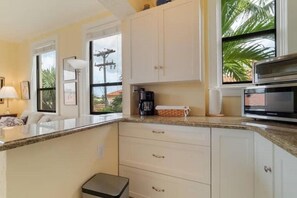 A kitchen with white cabinets, a countertop, a coffee maker, and a microwave.