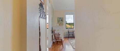 A hallway with a wooden floor leading to a dining area with two chairs and a table.