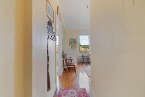 A hallway with a wooden floor leading to a dining area with two chairs and a table.