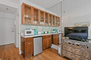 A compact kitchen with wooden cabinets, a microwave, a dishwasher, and a TV. - Pool/StepsToBeach/Dine/MoodStudioCONDO (Palm Beach)