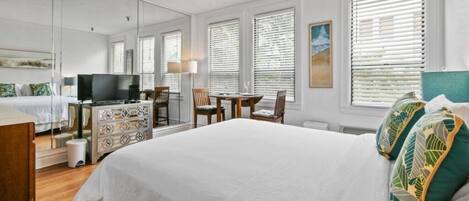 A hotel room with a large bed, a TV, a desk, and a chair.