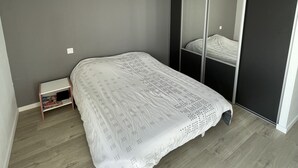 Un dormitorio con cama, ventilador de techo, armario y una mesita de noche.