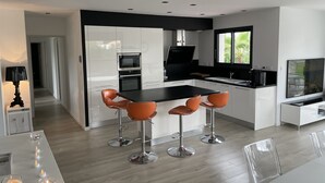 Una cocina moderna con una isla central, taburetes de bar y una mesa de comedor.