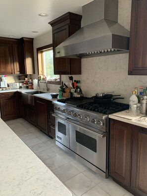 A modern kitchen with dark wood cabinets, stainless steel appliances, and a large window providing natural light.