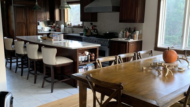 Uma cozinha moderna com armários de madeira, uma ilha central e um espaço de jantar com mesa e cadeiras de madeira.