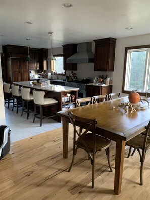 A modern kitchen with wooden cabinets, a central island, and a dining area with a wooden table and chairs. - Mountain Retreat Close to Windham/ Hunter Ski Resorts<br> (East Jewett)