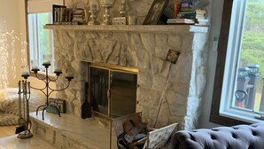 Uma sala de estar acolhedora com lareira de pedra, sofá confortável e vista para o exterior.
