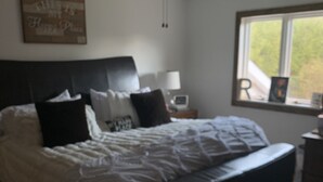 Quarto com cama, ventilador de teto, janela e mesa de cabeceira com abajur.
