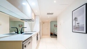 Una cocina moderna con armarios blancos, un lavamanos doble y vistas al área de estar contigua.