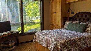 Een slaapkamer met een bed, een houten garderobe en een plafondventilator.