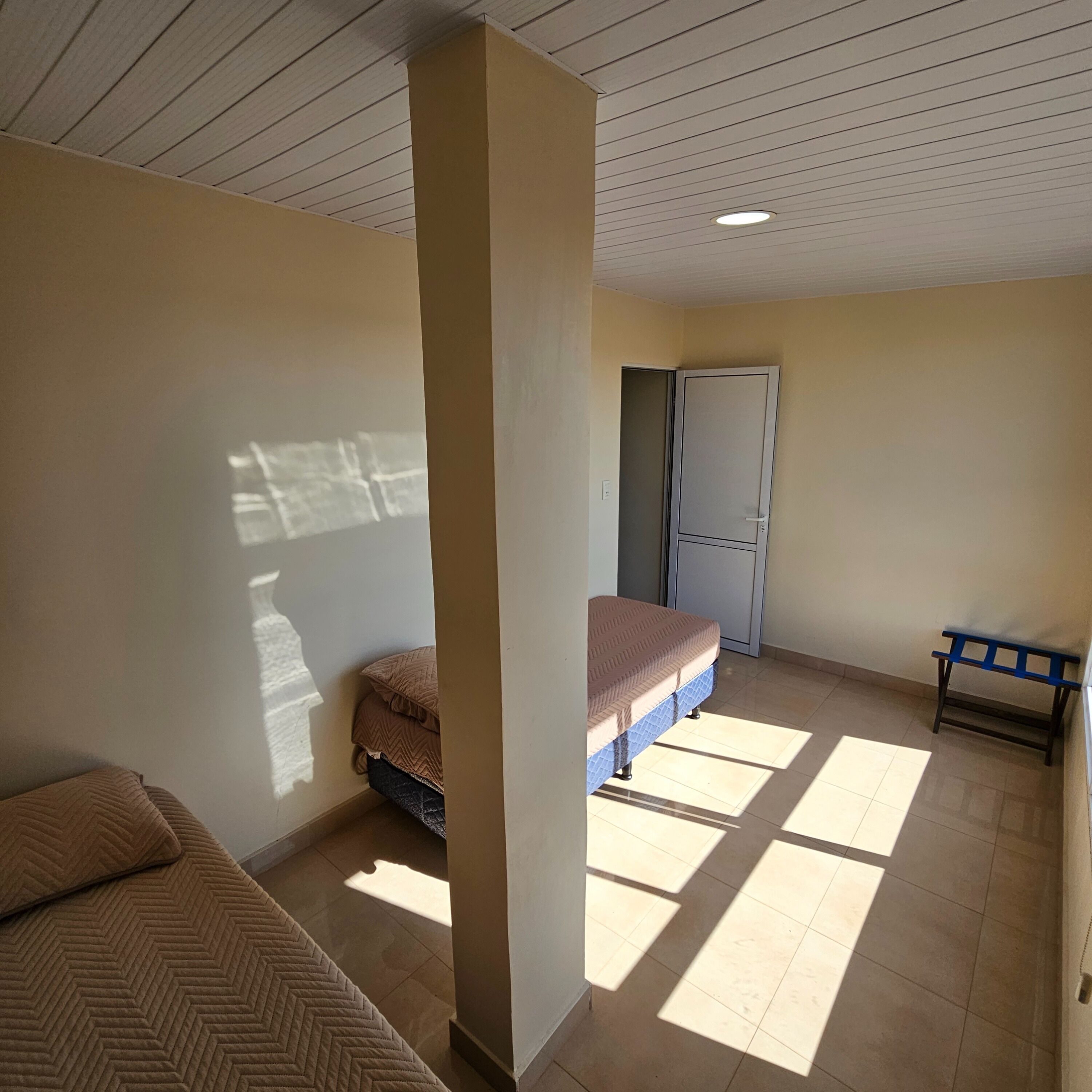 A room with a bed, a bench, and a door.