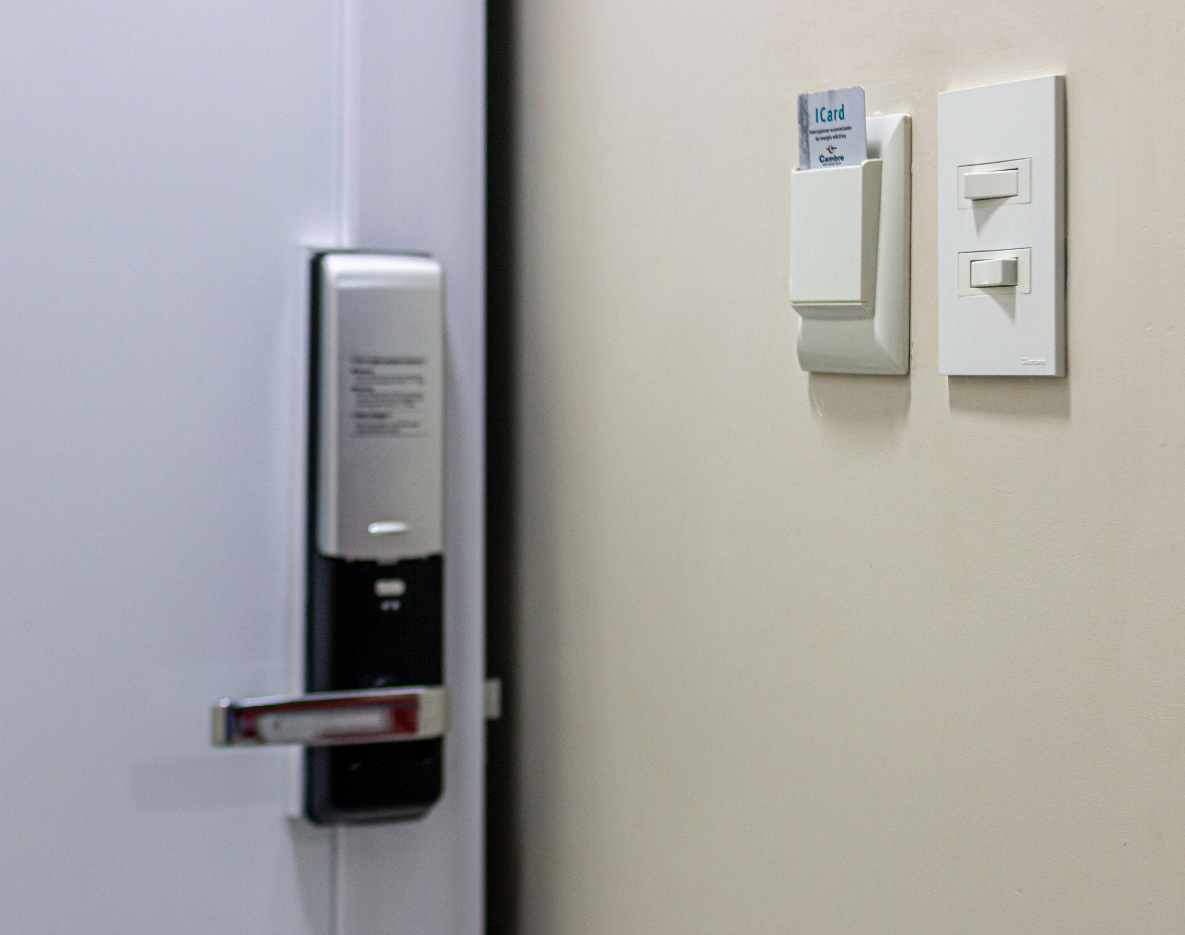 A door with a card reader and a wall-mounted light switch.