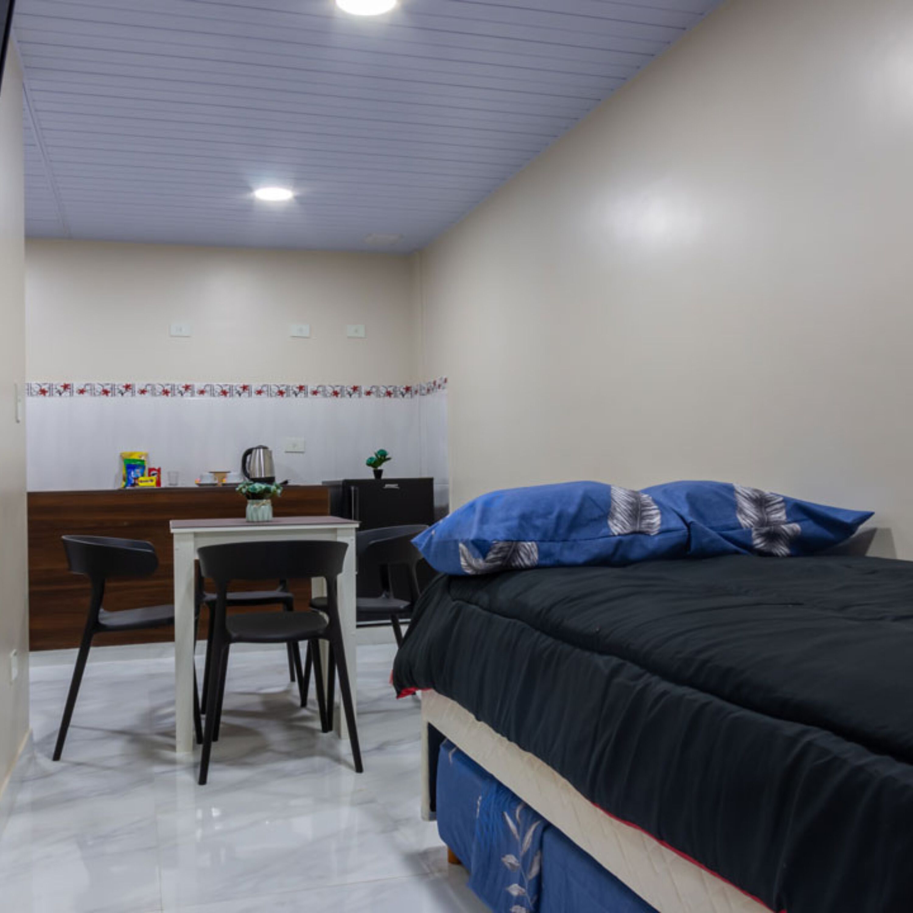 A bedroom with a bed, a desk, and a chair.