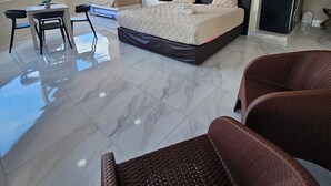 Een moderne slaapkamer met een groot bed, een bureau en rieten stoelen.