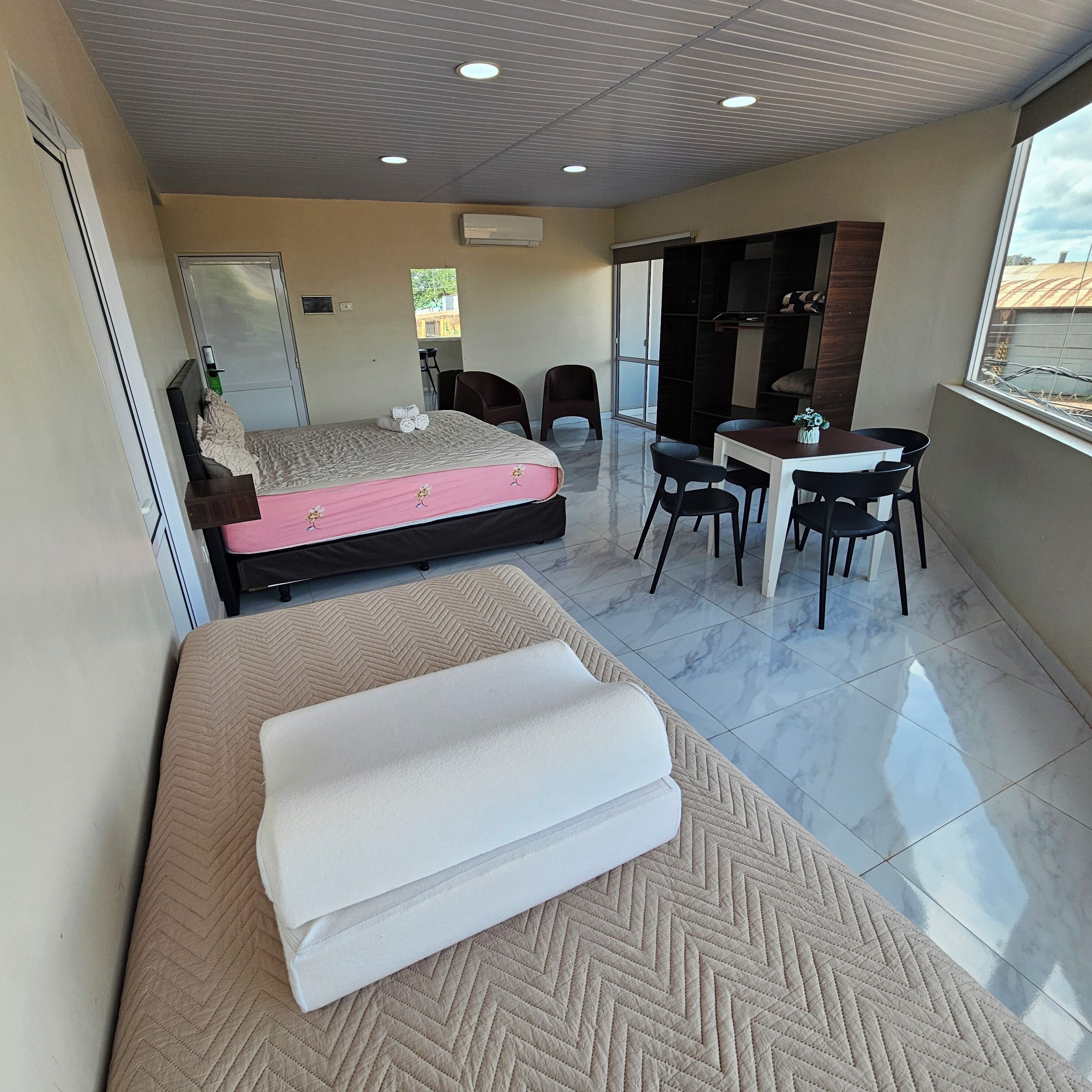 Una habitación de hotel moderna con una cama, una pequeña mesa de comedor y un sofá.