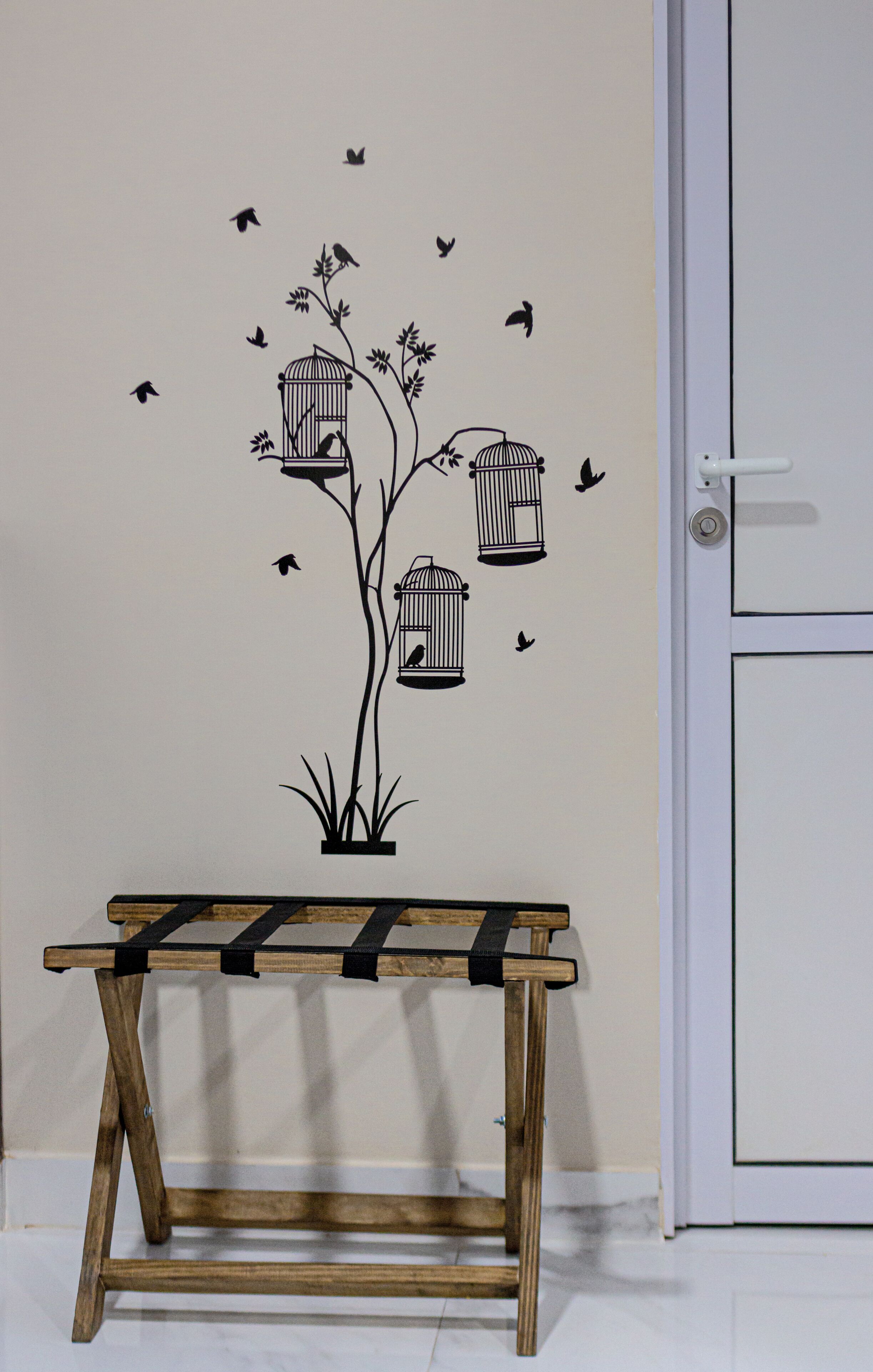 A wall with a bird-themed decal, a wooden bench, and a white door.