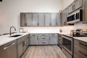 A modern kitchen with grey cabinets, a stainless steel sink, and a built-in oven.