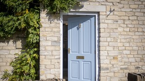 A stone building with a light blue door, a stone wall, and a tree with green leaves. - Saxon House, Harome, North York Moors (Harome)