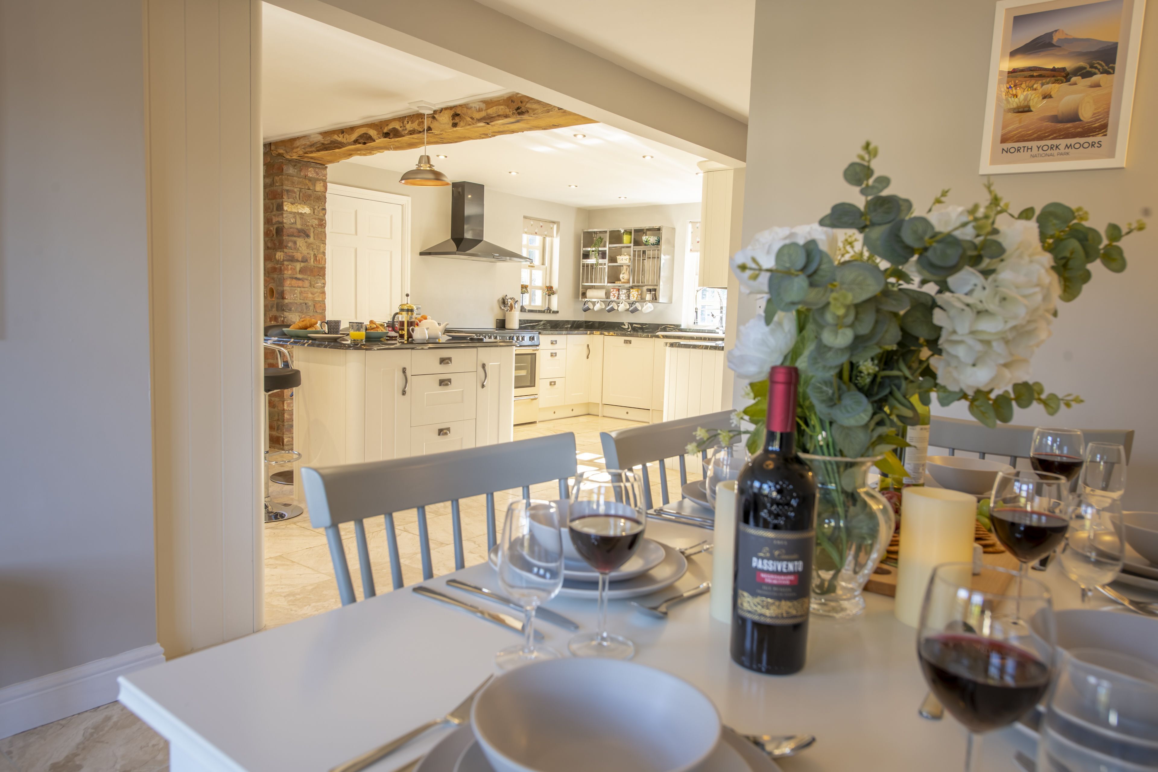 A dining area with a table set for a meal, a bottle of wine, and a vase of flowers.