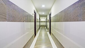 A long, narrow hallway with marble walls and a polished floor, leading to a bright, well-lit end. - Itsy Hotels Aura Stays (Hyderabad)