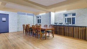 A dining area with a wooden table and chairs, a marble wall, and a counter with kitchenware. - Itsy Hotels Aura Stays (Hyderabad)