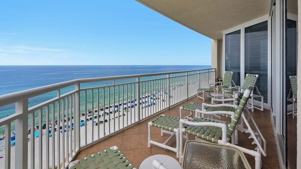 A balcony with white railings, green cushioned chairs, and a view of the beach and ocean. - 🌅Gulf Front|-Beachfront Pool|3BR The Pearl 1201🌅 (Navarre)